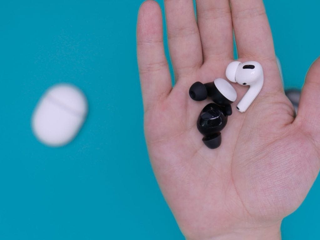 white and black earbuds on persons hand